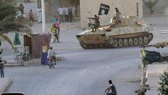 جنود من "تنظيم الدولة" يعتلون دبابة ويسيرون بأحد شوارع مدينة كوباني السورية  - أرشيفية