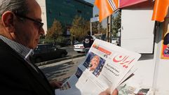 إيراني يقرأ إحدى الصحف المحلية مع صورة ترامب - أ ف ب