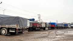 شاحنات تحمل مساعدات للسوريين تقف على الحدود التركية بسبب اشتباكات داعش (الأناضول)