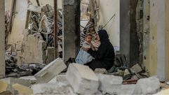 فلسطينية تجلس بين ركام منزلها مع رضيعتها في غزة- جيتي
