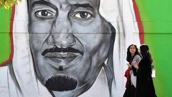سعوديتان تسيران بجانب جدارية للملك سلمان في الرياض - جيتي