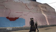 سيدة روسية تسير أمام جدارية لخارطة شبه جزيرة القرم- جيتي