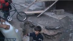 طفل في مخيم اليرموك في دمشق يملأ المياه من حفرة في الأرض