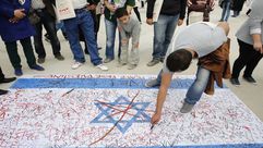 شبان تونسيون يرسمون العلم الإسرائيلي على الأرض خلال فعالية مناهضة للاحتلال- جيتي