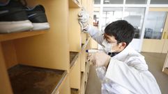 عامل ياباني يقوم بتعقيم خزائن في إحدى المؤسسات لمكافحة المرض- وكالة كيودو اليابانية