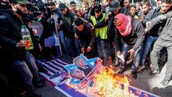 متظاهرون فلسطينيون يحرقون صورا لترامب ونتنياهو  في مظاهرة في غزة - جيتي