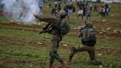جندي إسرائيلي يرمي عبوة مسيلة للدموع باتجاه متظاهرين ضد المستوطنات - جيتي