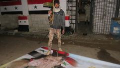 مقاتل من المعارضة يدوس صورة رئيس النظام السوري معبر نصيب - الأناضول