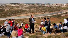 مدرس فلسطيني يلقي درسا أمام جدار إسمنتي يفصله عن مستوطنة إسرائيلية في الضفة الغربية أف ب