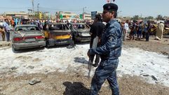 شرطي عراقي يقف أمام سيارات تعرضت لتفجيرات - ا ف ب