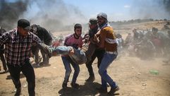 فلسطينيون يحملون جريحا في غزة مسيرة العودة - جيتي