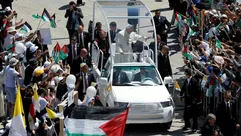 البابا فرنسيس يحيي الحشد من سيارته البابوية عند وصوله لترأس قداس في الهواء الطلق خارج كنيسة المهد في بيت لحم في 25 أيار/مايو 2014