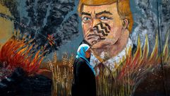 فلسطينية في غزة تسير أمام جدارية تهاجم ترامب وصفقة القرن- جيتي