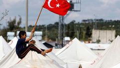 طفل سوري بأحد مخيمات اللاجئين يرفع العلم التركي- أرشيفية