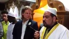 إمام المسجد خلال تلقينه الصحفي الشهادتين- يوتيوب