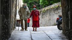 صورة ملتقطة في العاشر من حزيران/يونيو 2020 تظهر مسنان يضعان كمامات ويمشيان يدا بيد في بيرغامو في إيط