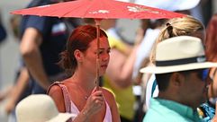 إيطالية تلجأ للمظلة من أجل الاحتماء من حرارة الشمس- جيتي