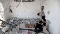شاب من غزة يجلس وسط منزله المدمر بفعل القصف - الأناضول