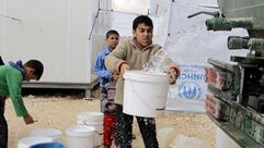 أطفال سوريون يتزودون بالماء من شاحنة بمخيم في الأردن- (أرشيفية) أ ف ب