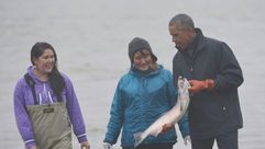 الرئيس اوباما يحمل سمكة سلمون اثناء لقائه صيادين واسرهم في الاسكا في 2 ايلول/سبتمبر 2015
