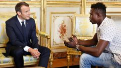 الرئيس الفرنسي إيمانويل ماكرون (يسار) متحدثا الى مامودو غاساما (22 عاما) من مالي في قصر الاليزيه في 