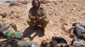 احد عناصر داعش يلتقط صورة بجانب جثث قتلى للنظام في حقل الشاعر - أرشيفية