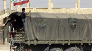 شاب في دير الزور يرفع علم إيران مع دخول مساعدات جيتي
