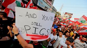 متظاهر لبناني يرفع لافتة لشتم المسؤولين في بلاده- جيتي