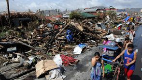 أطفال يسيرون في الفلبين بجانب الجثث بعد اعصار هايان - أ ف ب