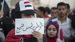 عراقية تحمل لافتة وسط التظاهرات بالعاصمة العراقية بغداد- جيتي