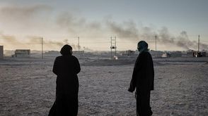 امرأتان تراقبان تصاعد الدخان من الضربات الجوية شرق الموصل