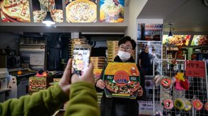 زبون يلتقط صورة أمام صورة لمخرج فيلم "باراسايت" بونغ جون-هو في مطعم "سكاي بيتزا" في سيول في 13 شباط/