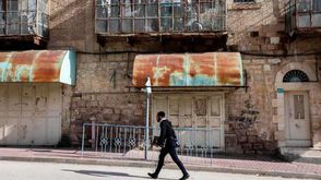 مستوطن إسرائيلي يسير عبر منزل فلسطيني في الخليل - جيتي