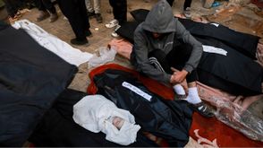 فلسطيني ينظر إلى رضيع قضى مع عائلته شهيدا بمجزرة رفح فجر الاثنين- جيتي