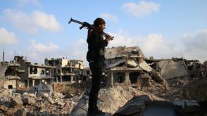 مقاتل من المعارضة في سوريا يقف على ركام الحرب - جيتي