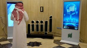 موظف في وزارة الداخلية السعودية يقف أمام شاشة تعرض شعار تطبيق ابشر - جيتي