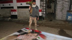 مقاتل من المعارضة يدوس صورة رئيس النظام السوري معبر نصيب - الأناضول