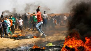 شاب فلسطيني يرشق جنود الاحتلال بالحجارة في مسيرة العودة- جيتي