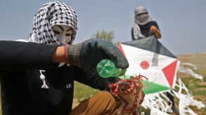 شبان من غزة يشعلون قماشا مربوطا بطائرة ورقية لإطلاقها لمهاجمة الاحتلال- جيتي