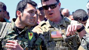 ضابط أمريكى يتحدث مع مقاتل من وحدات حماية الشعب الكردية - أ ف ب