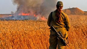 مجندة للاحتلال تقف أمام حقل قمح يحترق بفعل طائرة ورقية أطلقت من غزة- جيتي