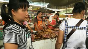 باعة يقفون خلف أكوام من لحم الكلاب في سوق في مدينة يولين الصينية