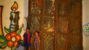أطفال يقفون أمام جدارية في غزة - أ ف ب