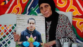 والدة الشهيد إياد الحلاق ترفع صورة ابنها بعد قتله- تويتر