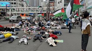 متظاهرون يابانيون استلقوا في الشارع ومكثوا بصمت دون حراك مرتدين ملابس ملطخة بالدماء ورفعوا أعلام فلسطين - الأناضول
