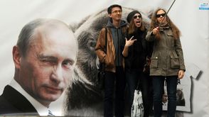 شبان يلتقطون صورة سيلفي امام ملصق للرئيس الروسي فلاديمير بوتين في سانت بطرسبورغ