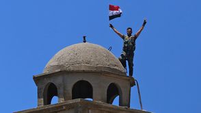 جندي سوري يرفع علم بلاده في القنيطرة فوق كنيسة القديس جورج الأرثوذكسية - جيتي