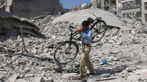 سوري يحمل دراجة وسط الأنقاض في حلب- أ ف ب