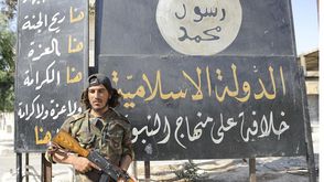مقاتل في الجيش الحر يقف بجانب شعار تنظيم الدولة