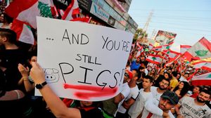 متظاهر لبناني يرفع لافتة تشتم المسؤولين في بلاده- جيتي